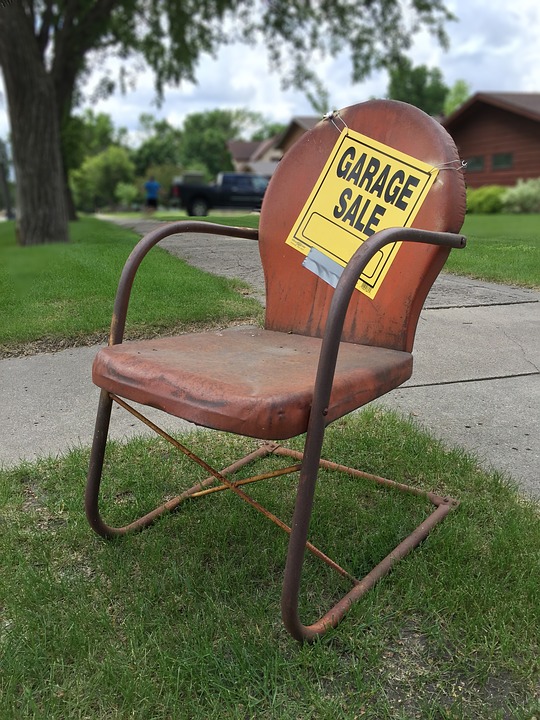 Picture of antique chair with garage sale sign taped to it. 